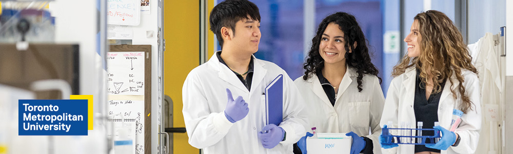A mixed race, mixed gender group of scientists in lab cots surrounded by science equipment